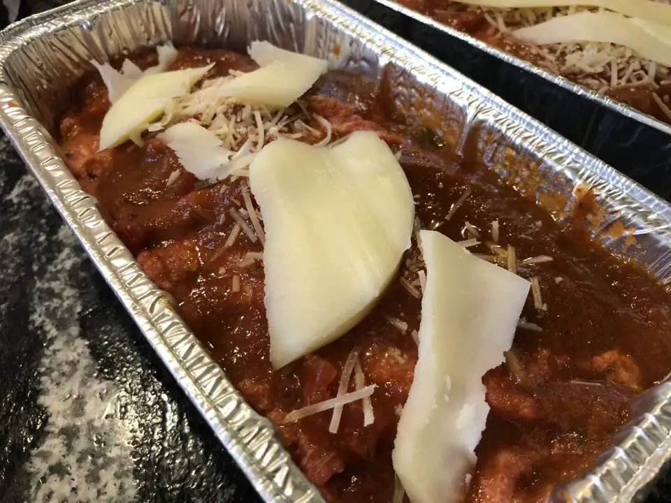 Meatloaf in loaf pan with sauce, parmesan, and thick cut provolone cheese