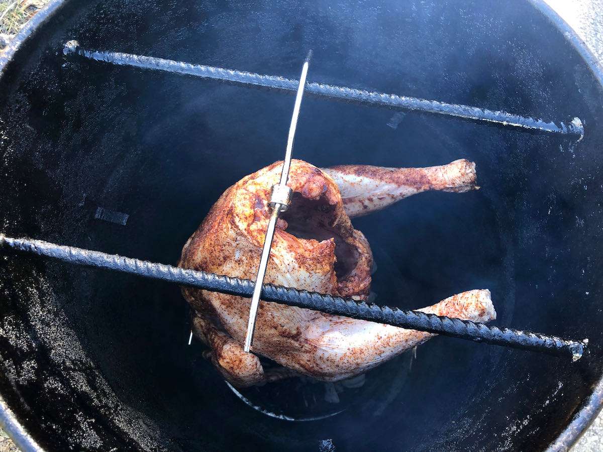 Seasoned turkey hanging on the Classic Pit Barrel Cooker using their Turkey Hanger Accessory.