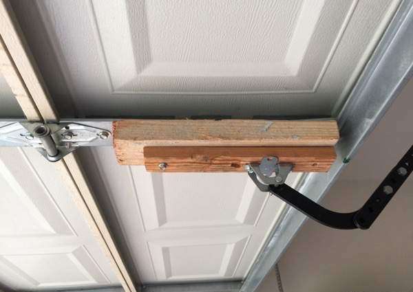Wood attached to garage door pick up arm center stile to reinforce the connection point