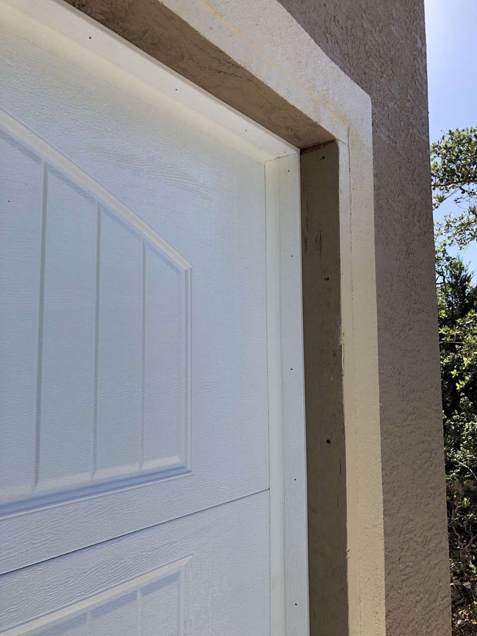 White vinyl trim installed on outside garage door jamb.