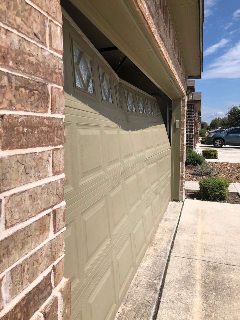 Builder grade garage door caved in because the automatic opener was activated with a broken spring.