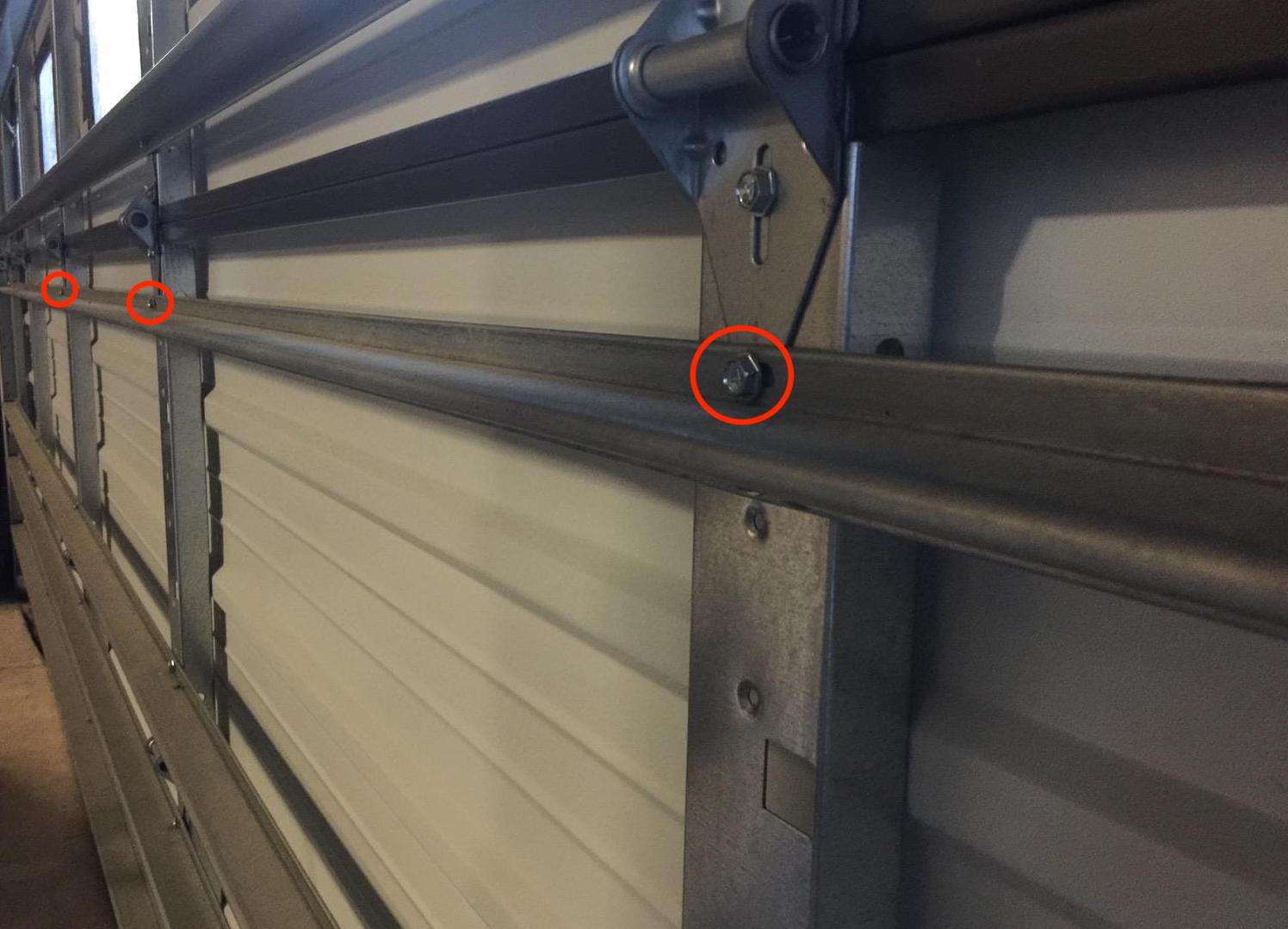 Remove the bottom screw on the garage door hinge and use it to attach the strut to the section. A second self tapping screw will need to be installed below it on the bottom of the strut.