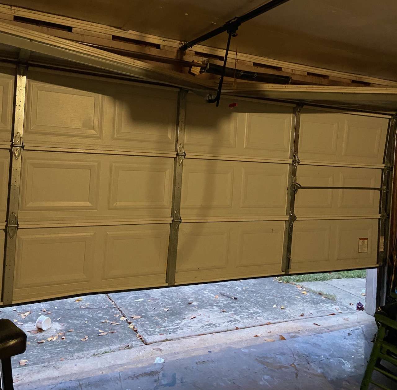 Top section and strut bent on double car width garage door due to homeowner closing garage door on a stool in the garage.