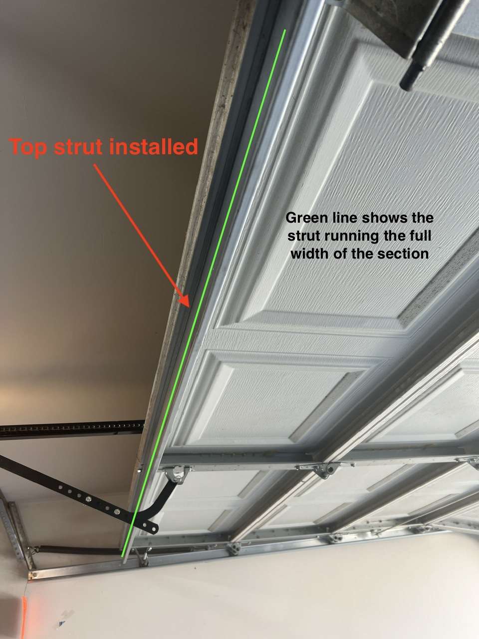 This image shows a top reinforcement strut installed on the top section of a single car garage door.