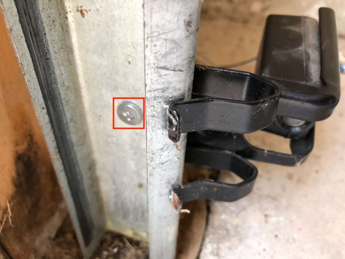 LiftMaster Chamberlain safety sensor brackets bolted to the vertical tracks. The bolt is outlined in the red square.