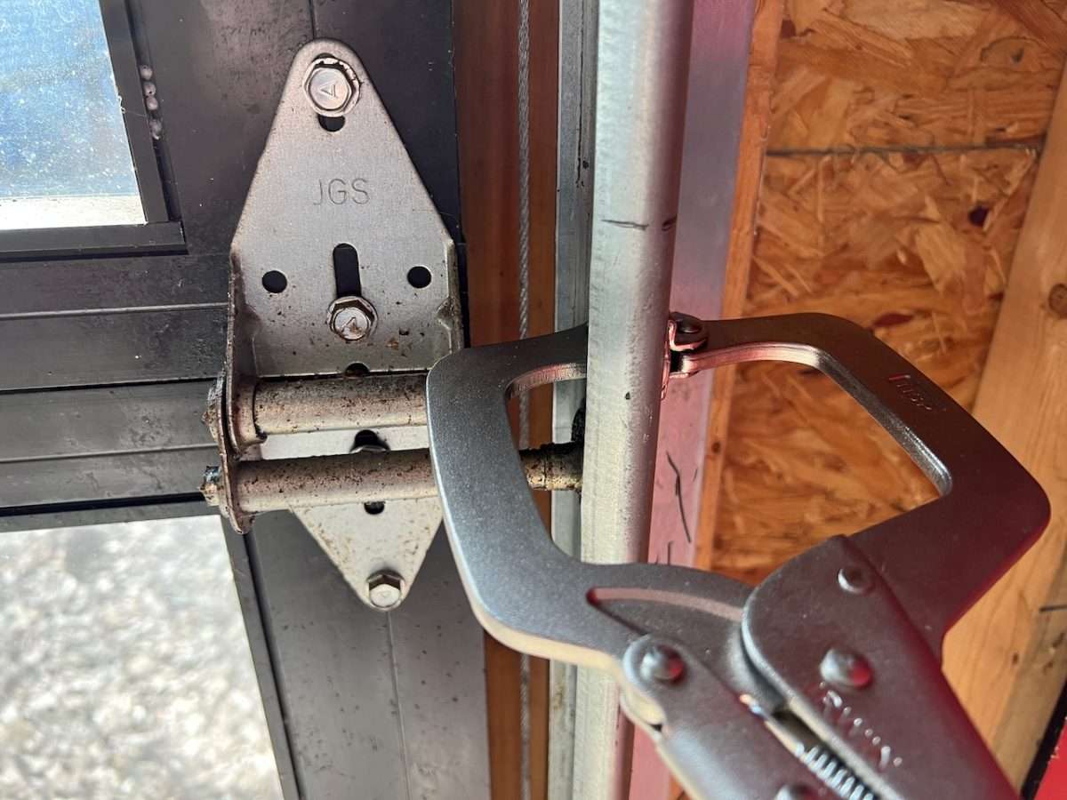C clamp Vise-Grips on garage door vertical track right above the roller.