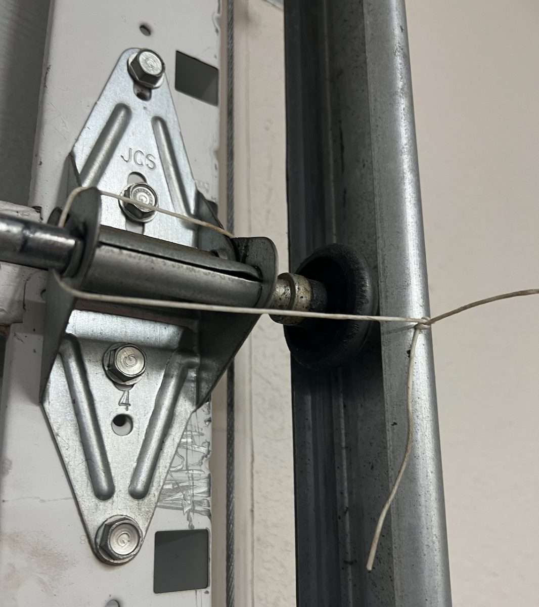 Wire securing garage door hinge to vertical track.