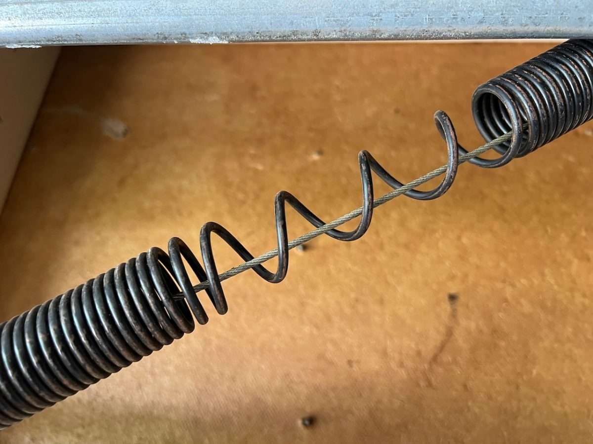 Sprung extension spring on a garage door with safety cable running through the center.