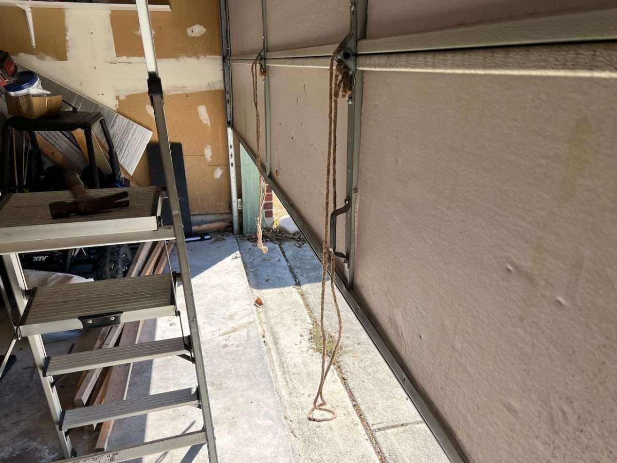 Rope attached to the garage door is breaking the safety sensor beam as the door closes causing it to reverse and go back up.